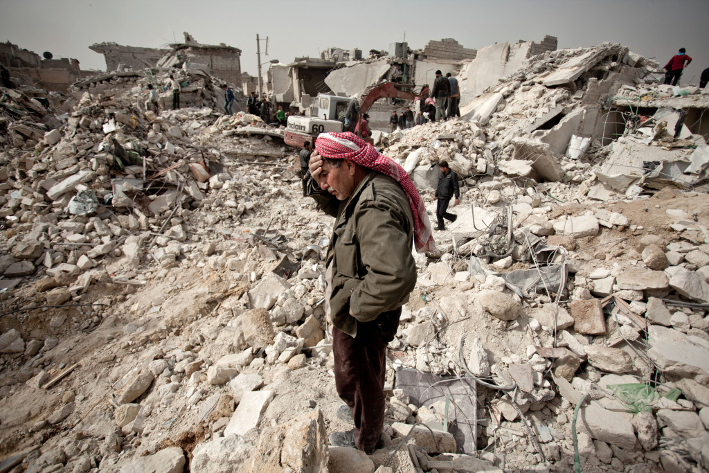 A Syrian man reacts while standing on the rubble of his house while others look for survivors and bodies in the Tariq al-Bab district of the northern city of Aleppo on February 23, 2013. Three surface-to-surface missiles fired by Syrian regime forces in Aleppo's Tariq al-Bab district have left 58 people dead, among them 36 children, the Syrian Observatory for Human Rights said on February 24. AFP PHOTO/PABLO TOSCO (Photo credit should read Pablo Tosco/AFP/Getty Images)